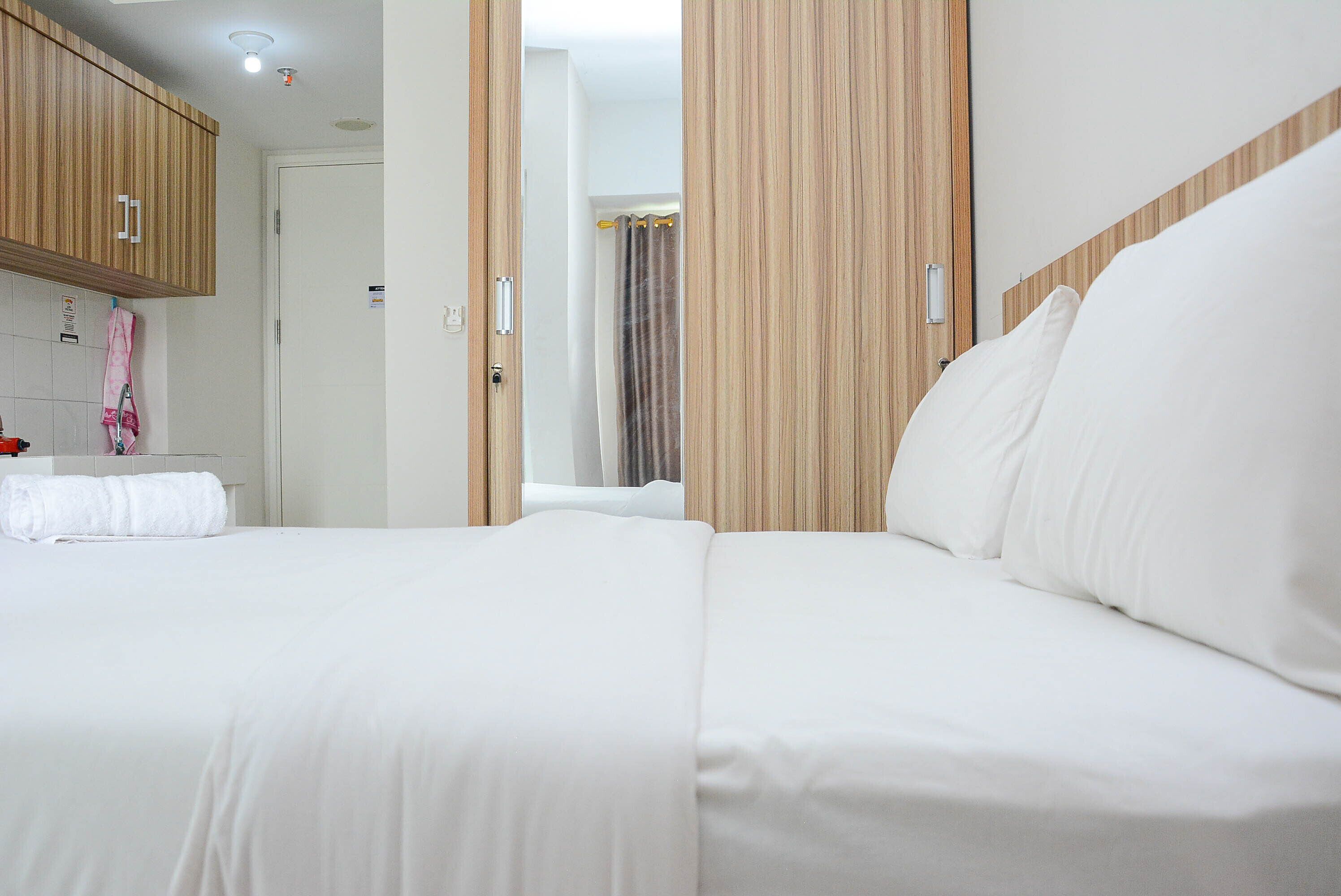 A hotel room with a large bed, wooden headboard, and a bathroom visible through an open door.
