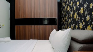A hotel room with a bed, a wooden wardrobe, and a floral wallpaper. - Gorgeous 2BR Springlake Summarecon Apartment (Bekasi)