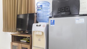 A water dispenser, a television, and a refrigerator in a hotel room. - Cozy Studio at Elvis Tower Apartment (Cikarang)