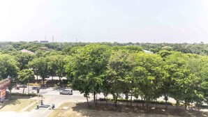 A parking area with trees and a signboard. - Cozy Studio at Elvis Tower Apartment (Cikarang)