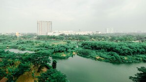 Ein großes Gebäude im modernen Stil, umgeben von einem üppigen Park und einer ruhigen Wasserfläche.