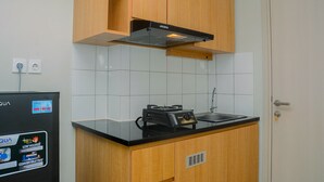 Cuina compacta amb armaris de fusta, taulell negre i fornel integrat.