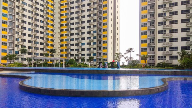 Una gran piscina de disseny corbat, envoltada d'edificis residencials alts amb balcons.