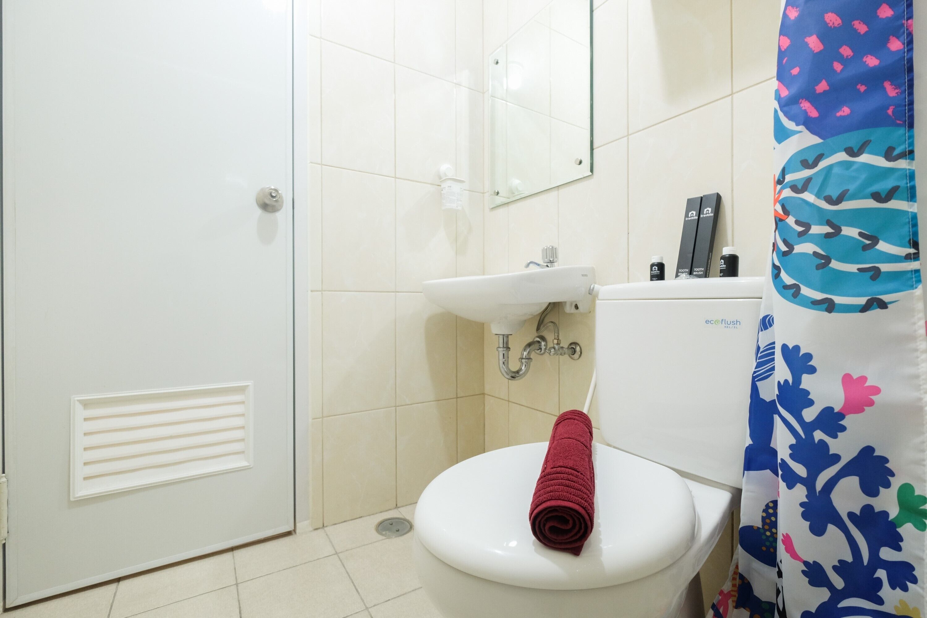 A bathroom with a white toilet, a sink, and a shower curtain with a floral pattern.