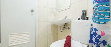 A bathroom with a white toilet, a sink, and a shower curtain with a floral pattern.
