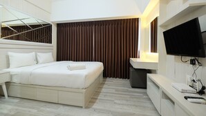 Una habitación de hotel moderna con cama, televisión, escritorio y ventana con cortinas.