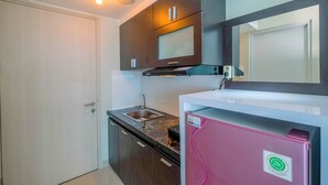 A compact kitchen with dark wooden cabinets, a stainless steel sink, and a pink refrigerator.