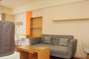 A modern living room with a grey sofa, a glass coffee table, and a white chair.