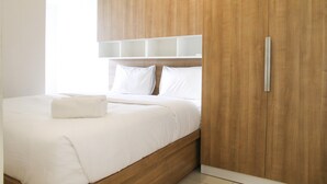 Quarto moderno com cabeceira de madeira, roupa de cama branca e guarda-roupa embutido.