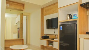A compact kitchen with a refrigerator, a microwave, and a flat-screen TV mounted on the wall. - Cozy and Relax 2BR at Meikarta Apartment (Cikarang)