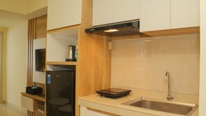 A modern kitchen with a built-in refrigerator, a microwave, and a stainless steel sink. - Cozy and Relax 2BR at Meikarta Apartment (Cikarang)