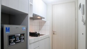A compact kitchen with a refrigerator, a stove, and a sink. - Homey Studio at Springlake Summarecon Bekasi Apartment (Bekasi)