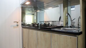 Una cocina moderna con encimera negra, pileta de acero inoxidable y muebles de madera.