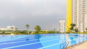 Una piscina con carriles azules, rodeada de un bordeado de baldosas y follaje.