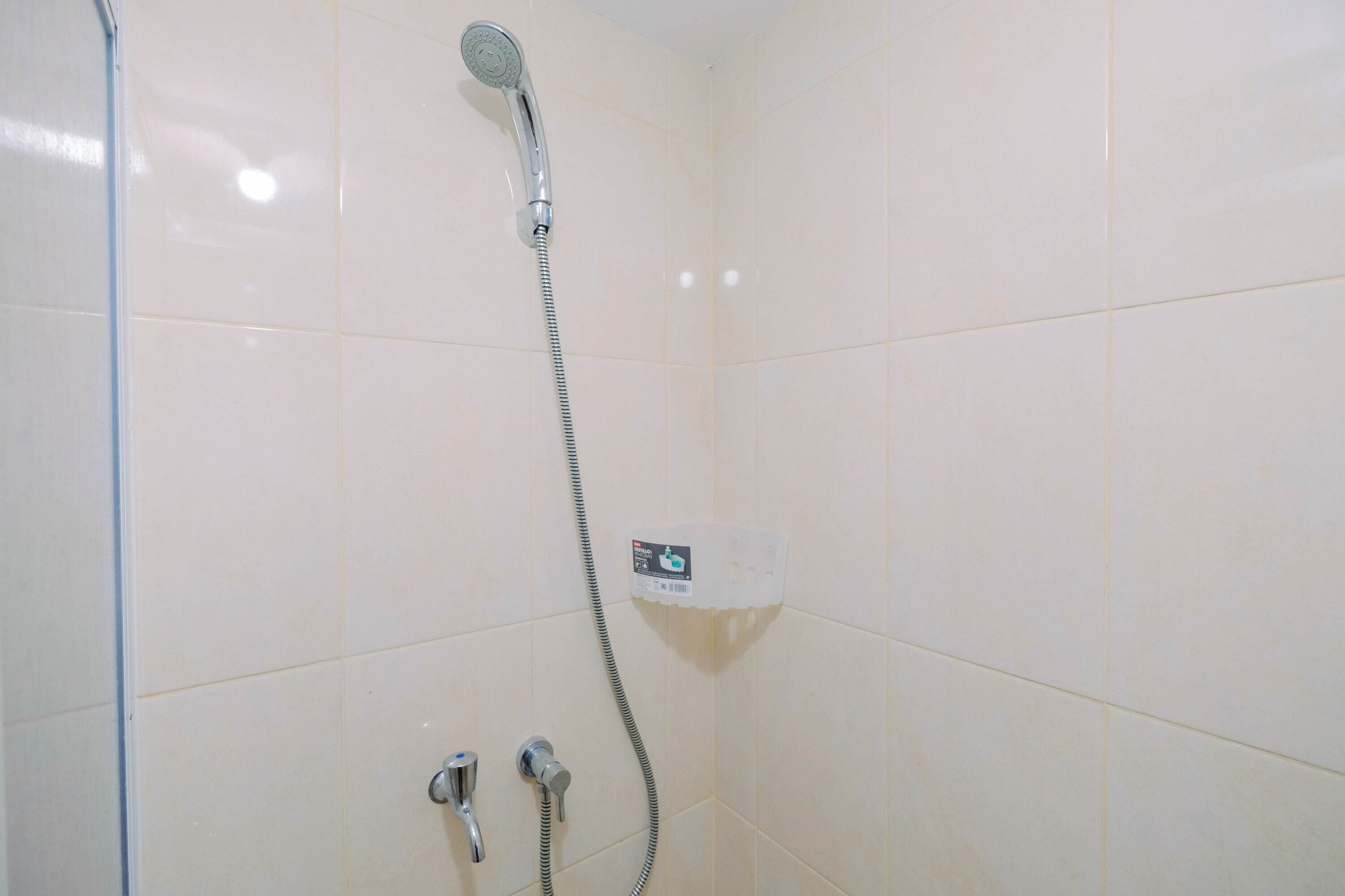 A shower with a handheld showerhead and a wall-mounted control panel.