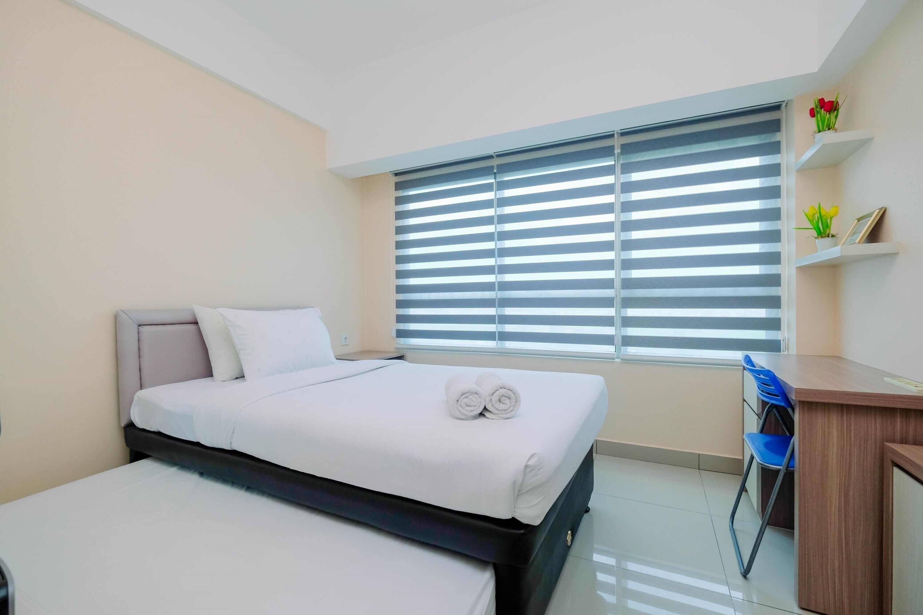 A hotel room with a bed, a desk, and a chair.