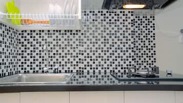 A kitchen with a black and white tiled backsplash, a stainless steel sink, and a gas stove.