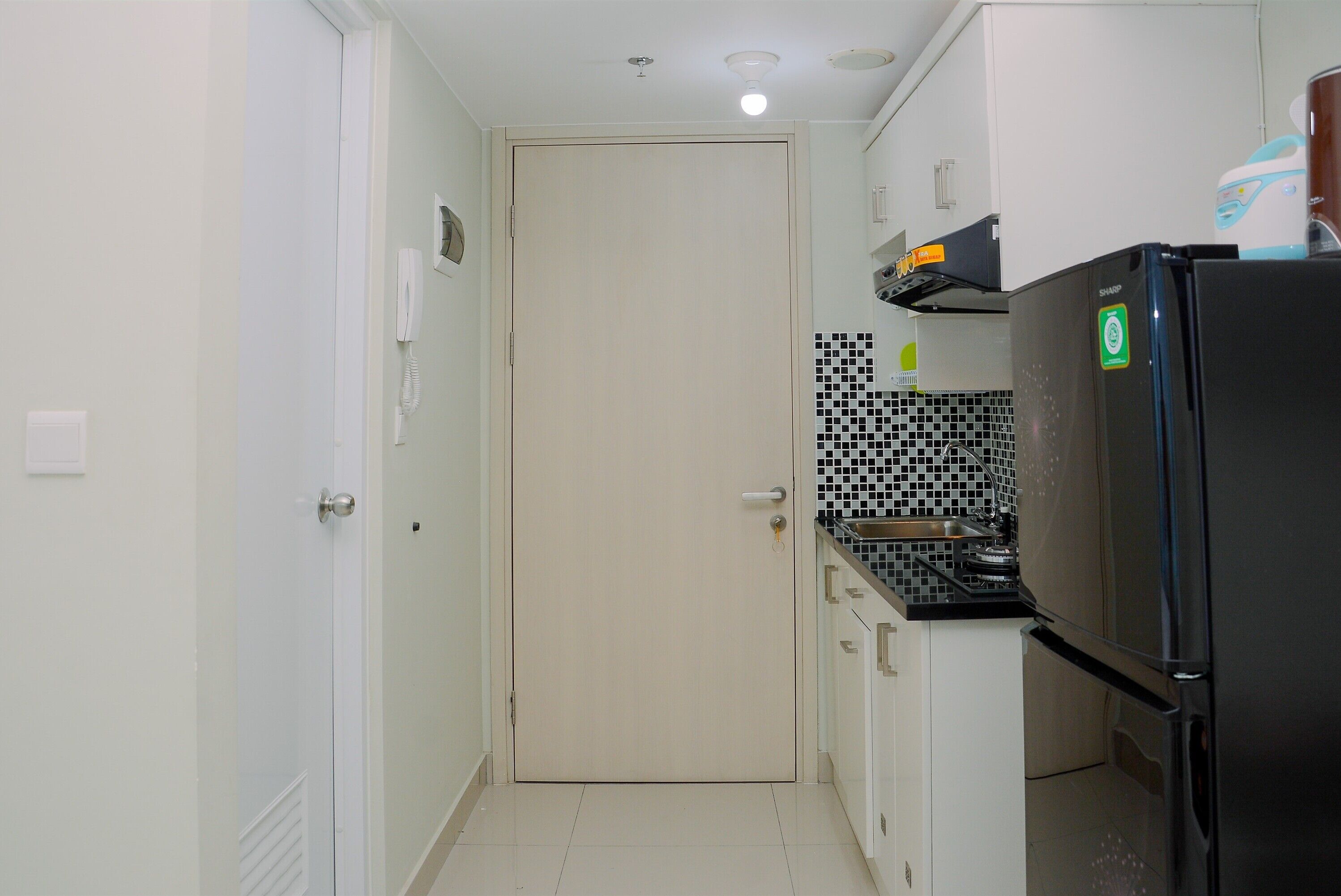 A compact kitchen with a refrigerator, stove, and white cabinets.