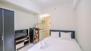 Une chambre d’hôtel équipée d’un lit, d’une télévision, d’une armoire et d’une petite kitchenette.