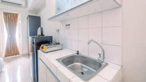 Une cuisine moderne dotée d’un évier en acier inoxydable, de murs recouverts de carreaux blancs et d’un four encastré.