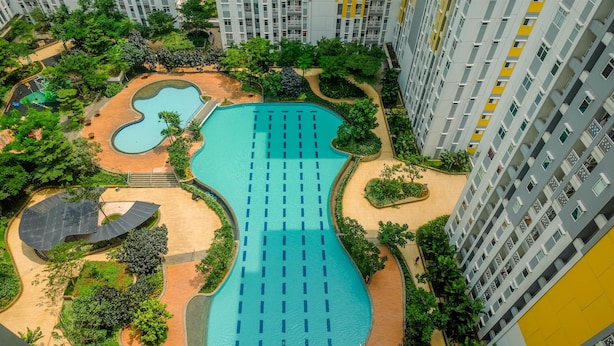 Une piscine dotée de plusieurs couloirs, entourée de verdure et située à proximité d’immeubles d’habitation de grande hauteur.