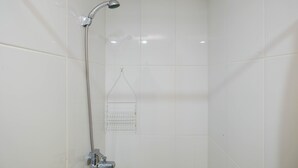 Eine Dusche mit Handbrause und Armatur an der Wand.