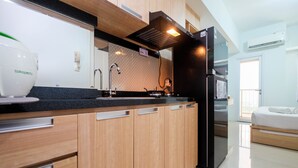 Eine moderne Küche mit Holzschränken, einem schwarzen Kühlschrank und einer Arbeitsplatte mit Wasserspender.