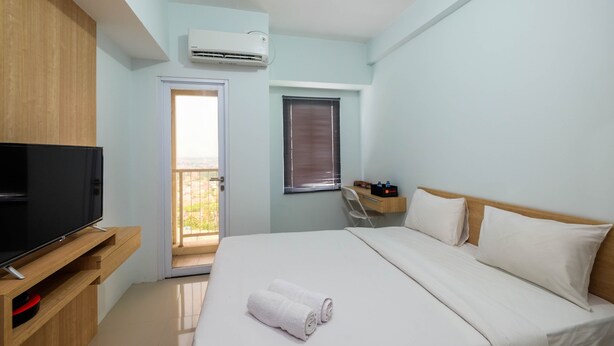 Ein Hotelzimmer mit Bett, Fernseher, Klimaanlage, Schreibtisch und Fenster.