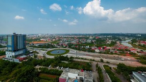Eine Luftaufnahme einer Stadtlandschaft mit einem markanten, blauen Gebäude, einer Kreisverkehr und einem Fluss.