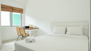 A hotel room with a large bed, two chairs, a desk, and a window with a view. - Homey Studio Margonda Residence 1 Apartment (Depok)
