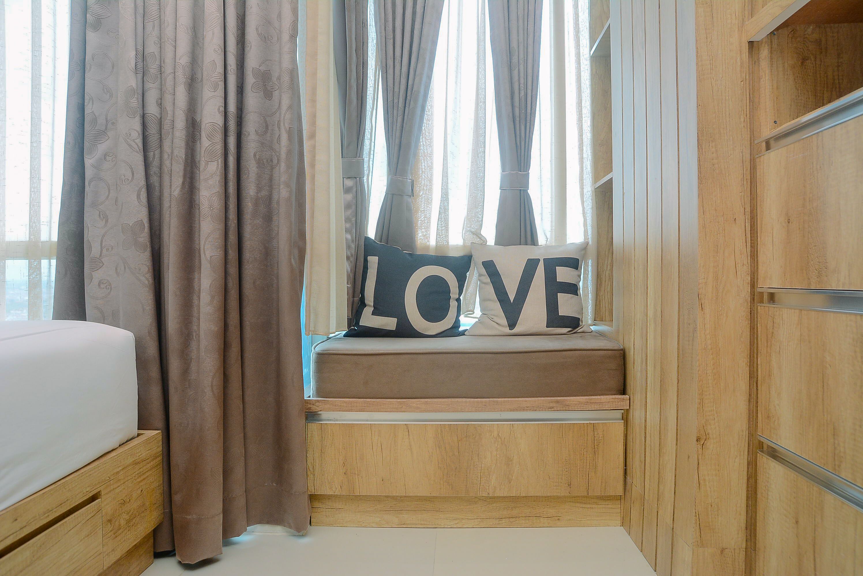 Een slaapkamer met een bed, een raam met gordijnen en een houten kledingkast.
