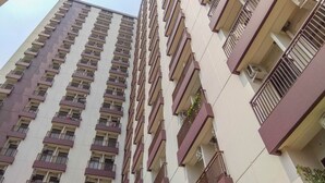 Een hoog appartementencomplex met meerdere balkons, airconditioners en een uniform architectonisch ontwerp.