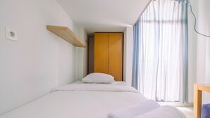 Een slaapkamer met een bed, een houten garderobe, een raam met gordijnen en een nachtkastje.