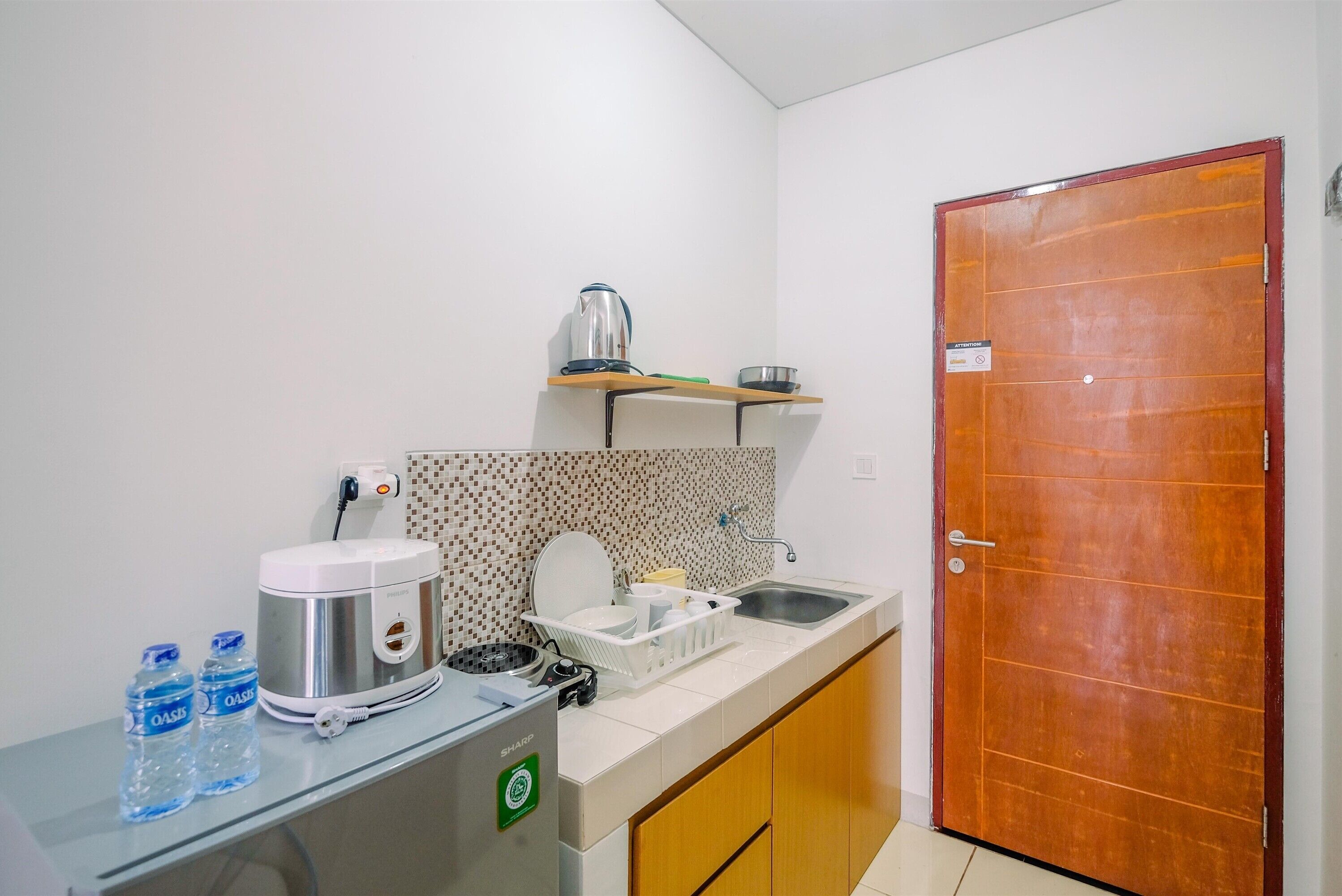 A compact kitchenette with a coffee maker, water bottles, a kettle, and a sink.