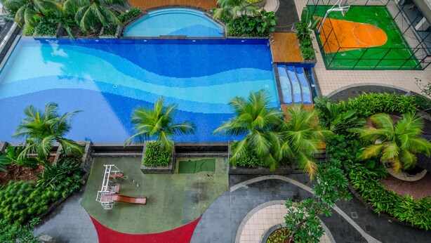 Una piscina rodeada de palmeras y una cancha de baloncesto.