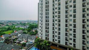 Un edificio residencial alto con varios balcones y vistas a un barrio residencial con casas y vegetación.
