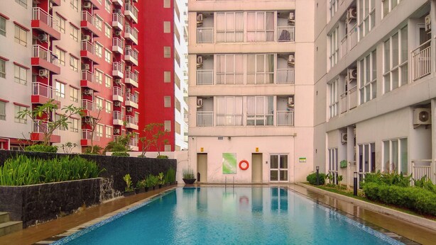 A swimming pool surrounded by multi-story residential buildings with balconies, a lifebuoy, and a sign indicating a no swimming zone.