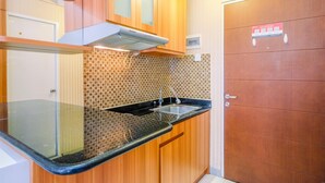 A kitchen with wooden cabinets, a black countertop, a stainless steel sink, and a tiled backsplash.