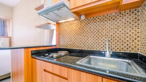 A kitchen with wooden cabinets, a black countertop, a stainless steel sink, and a tiled backsplash.