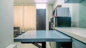 Un espacio habitable compacto con kitchenette, comedor y una puerta que da a una habitación contigua.