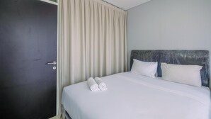 Una habitación de hotel con una cama, dos almohadas, una puerta y una cortina.