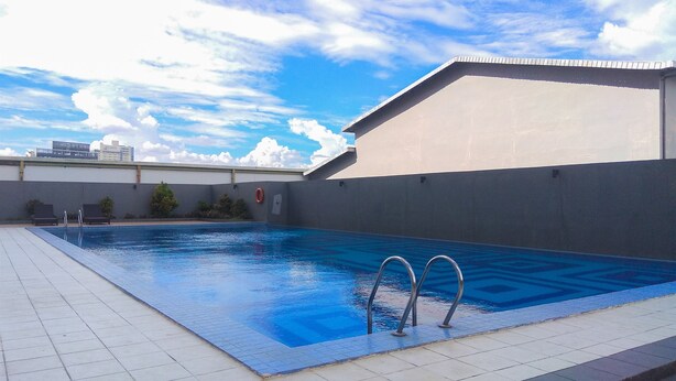 A swimming pool with clear blue water, surrounded by a tiled deck. - Warm and Cozy Studio Park View Condominium Apartment (Depok)