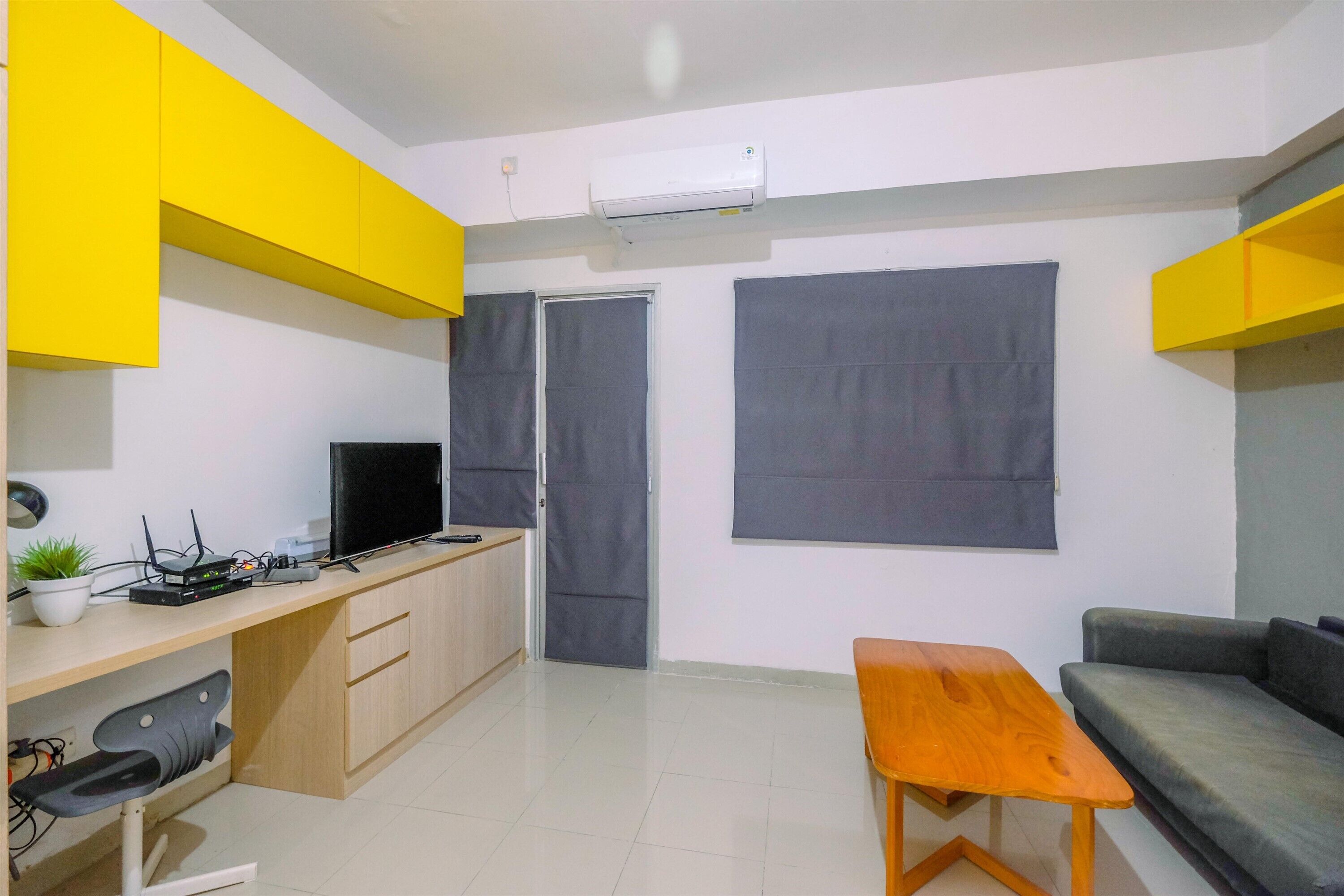 Un espacio habitable compacto con kitchenette, un sofá, una mesita y un televisor.