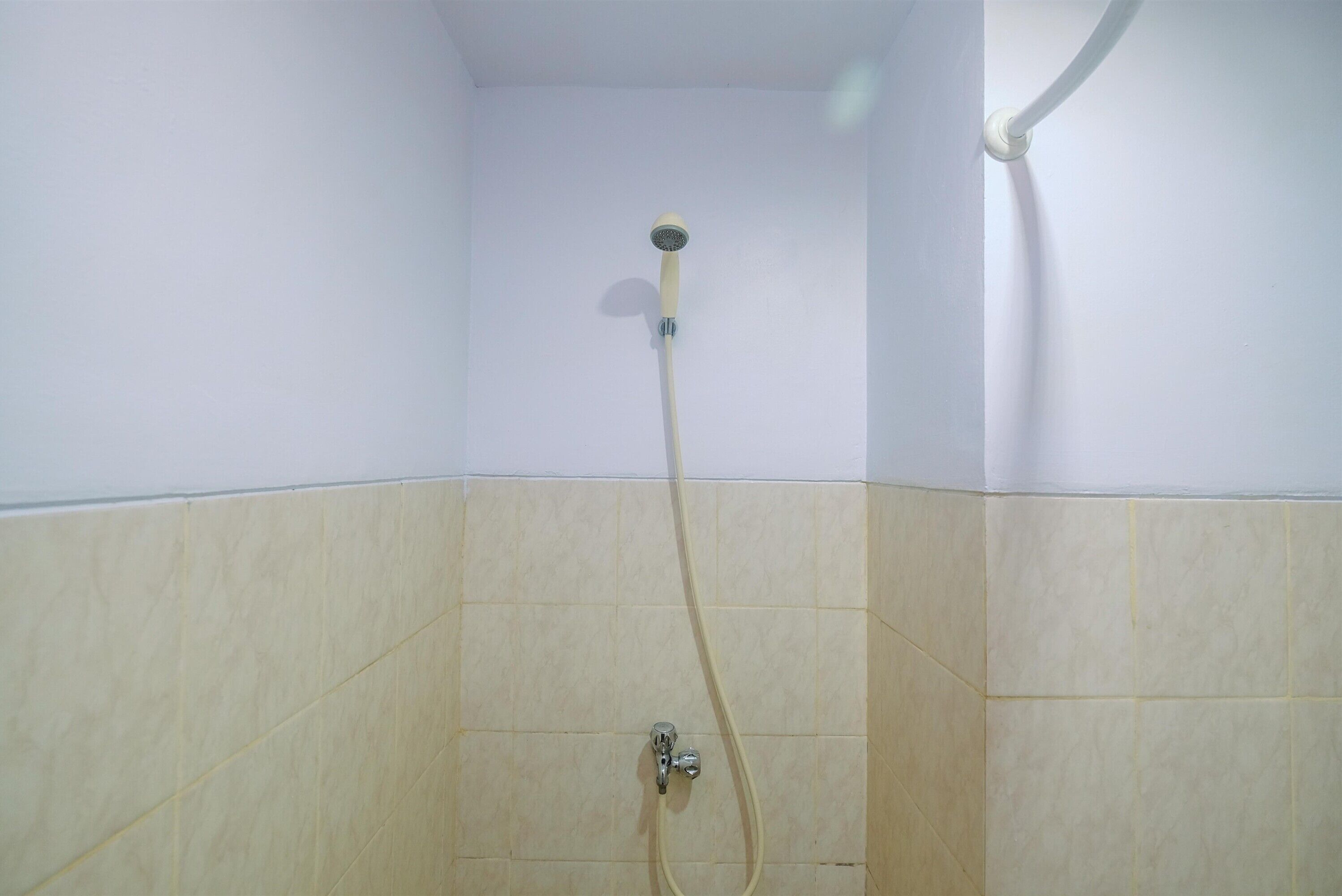 Eine Dusche mit Handbrause und Armaturen an der Wand.