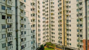 A high-rise residential building with multiple balconies and a central courtyard.