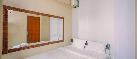 Una habitación de hotel con una cama grande, un espejo, una puerta y un equipo de aire acondicionado.