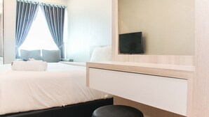 Ein Hotelzimmer mit Bett, Schreibtisch, Stuhl, Fernseher und einem fenster mit Vorhängen.