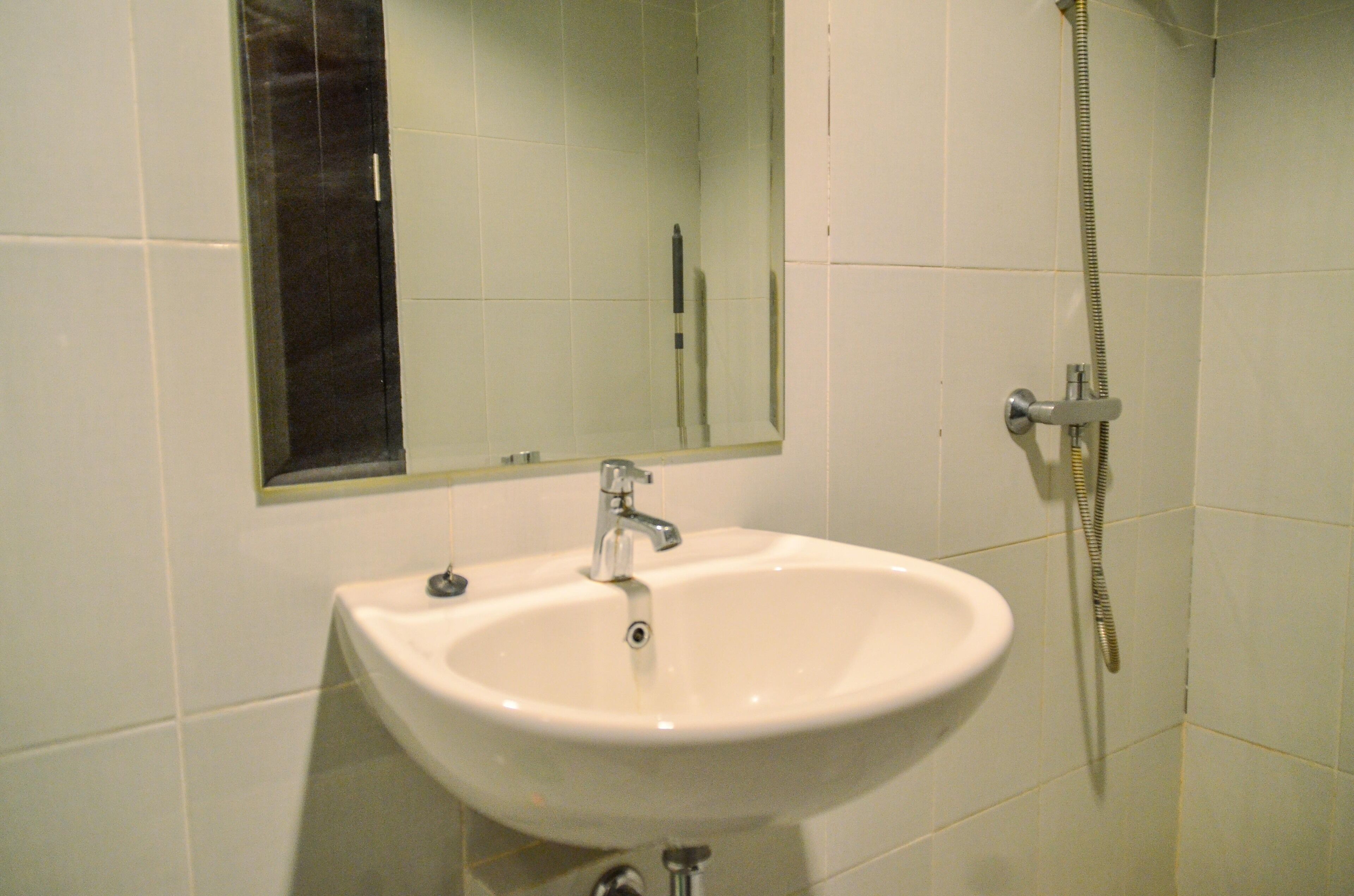 Un baño con lavamanos blanco, espejo y ducha.