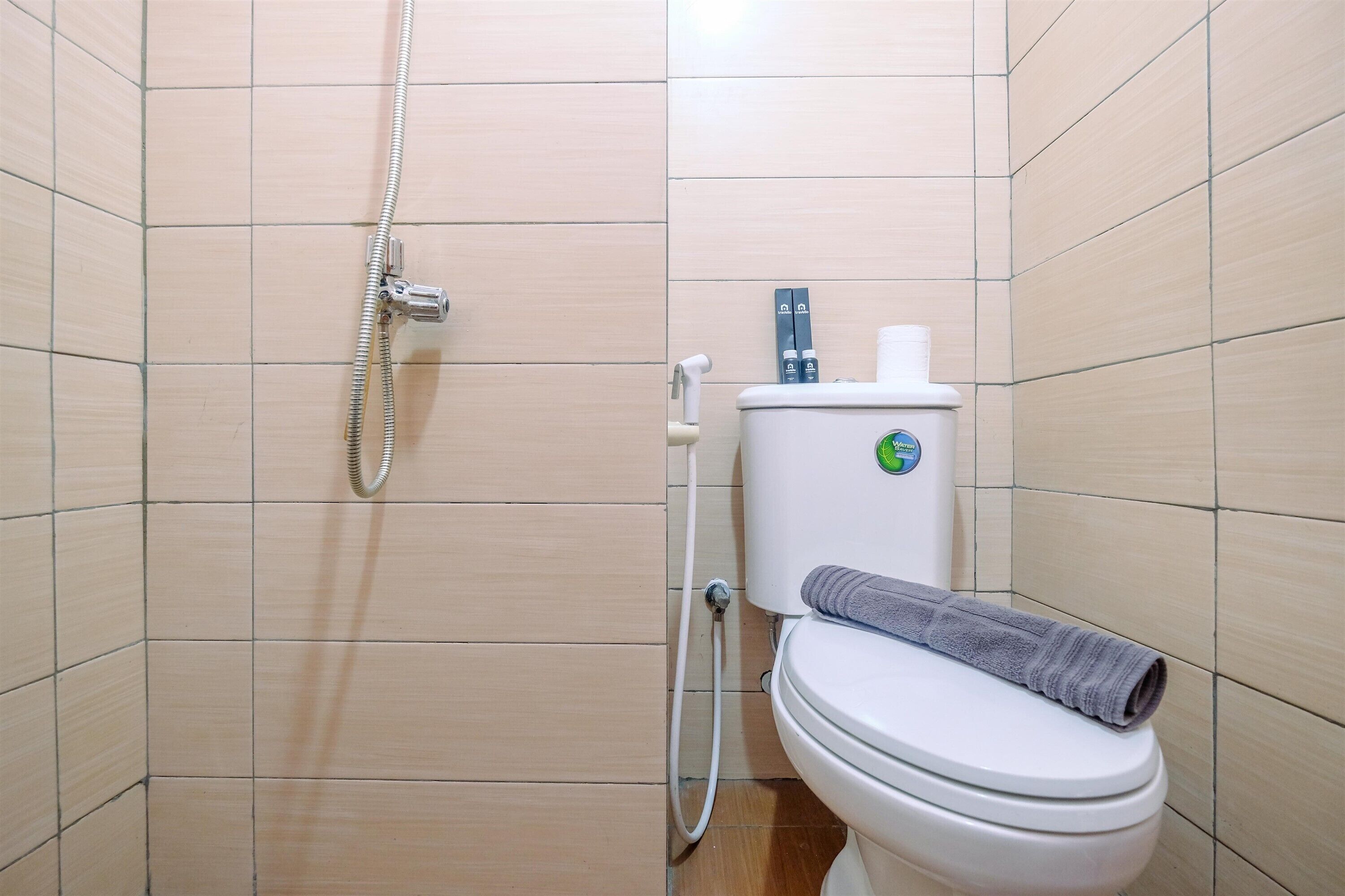 A small bathroom with a toilet, a shower, and a towel on the toilet seat.