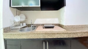 Eine Küche mit einer Granitarbeitsplatte, einem Spülbecken, einem Geschirrständer und einem schwarzen Schrank darüber.